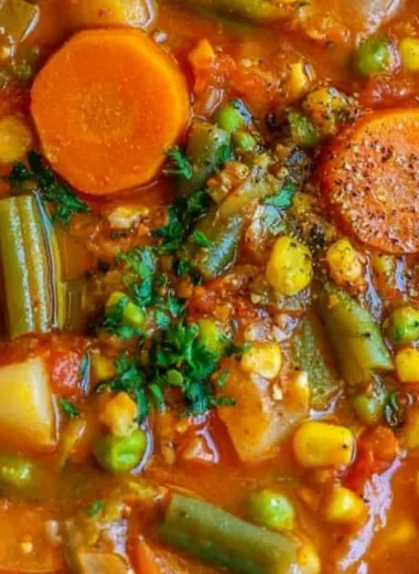 Bowl of cozy vegetable soup with fresh vegetables and herbs