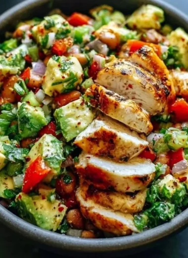 Bowl of creamy avocado chicken salad with fresh ingredients garnished on top