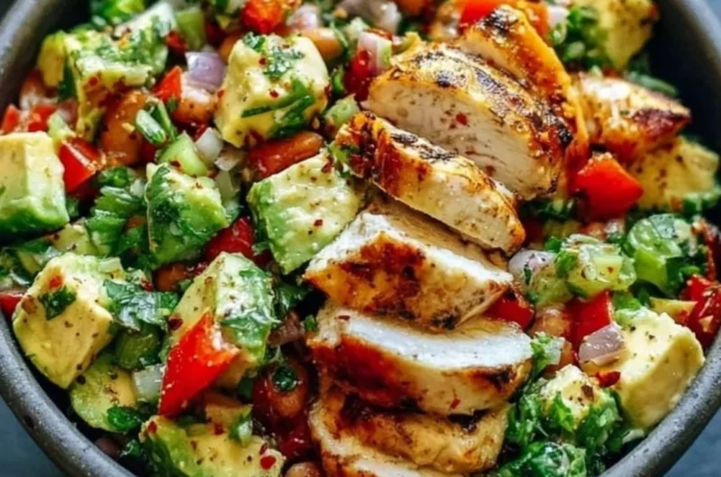 Bowl of creamy avocado chicken salad with fresh ingredients garnished on top
