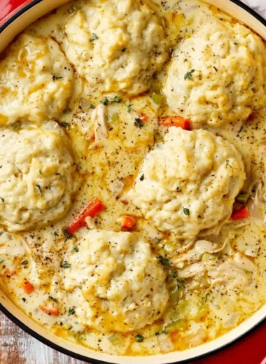 Bowl of creamy homemade chicken and dumplings served with herbs.