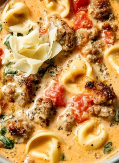 Bowl of creamy tortellini soup garnished with herbs and served hot