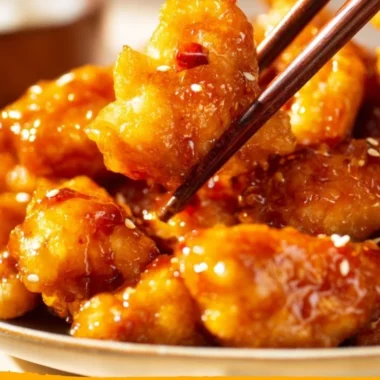 Crispy orange chicken served on a plate with garnishes and sauce