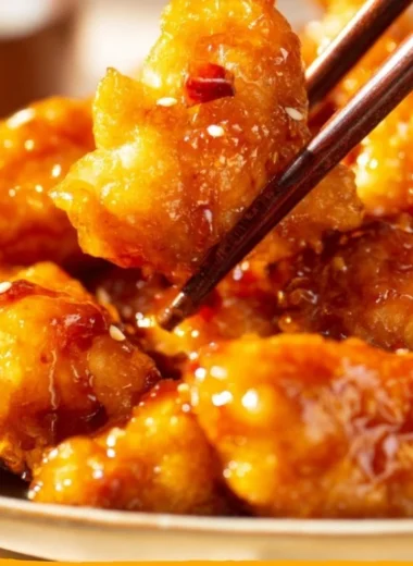 Crispy orange chicken served on a plate with garnishes and sauce