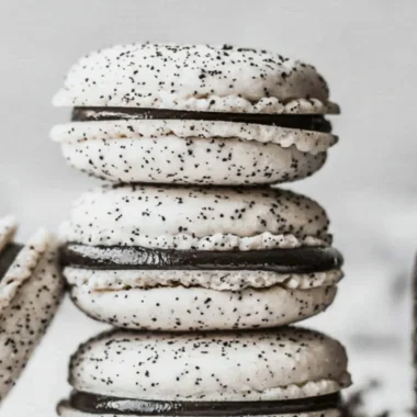 Delicious Oreo Macarons stacked on a plate, featuring chocolate cream filling.