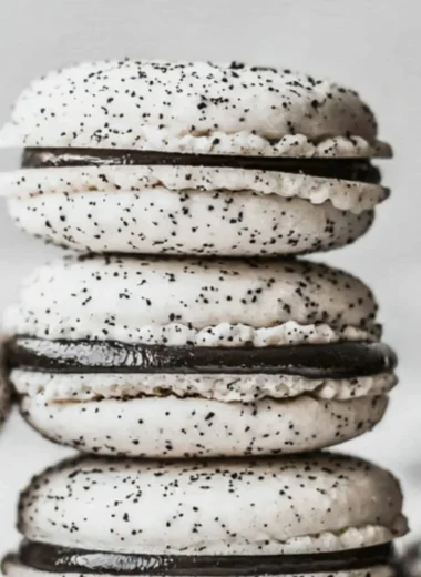 Delicious Oreo Macarons stacked on a plate, featuring chocolate cream filling.