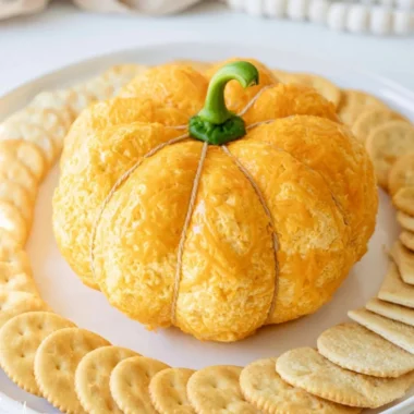Pumpkin shaped cheese ball appetizer on a serving platter