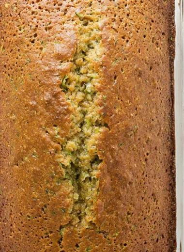 Two slices of moist zucchini bread on a wooden cutting board