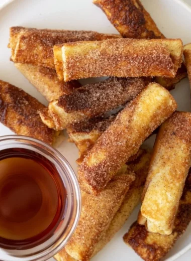 Delicious French Toast Roll-Ups served with syrup and powdered sugar.
