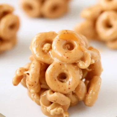 Bowl of peanut butter cereal bites with a spoon on a wooden table