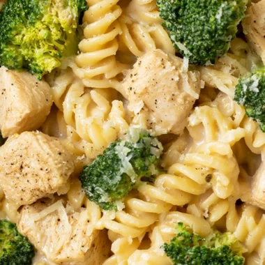 Cozy chicken broccoli pasta dish served in a bowl, garnished with parmesan cheese.