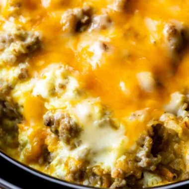 Cheesy sausage hashbrown breakfast casserole served in a baking dish.