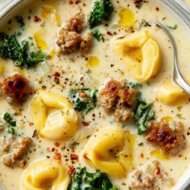 Bowl of creamy sausage tortellini soup garnished with fresh herbs
