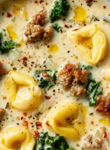 Bowl of creamy sausage tortellini soup garnished with fresh herbs