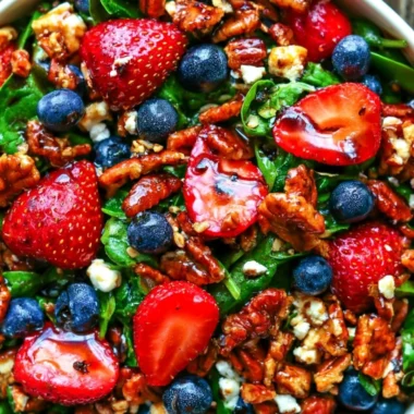 Delicious strawberry spinach salad with blueberries, pecans, and feta cheese in balsamic glaze.
