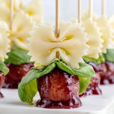 Bowtie pasta with cocktail meatball skewers on a serving platter.