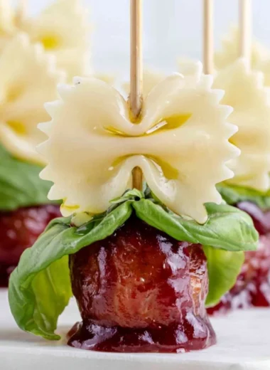 Bowtie pasta with cocktail meatball skewers on a serving platter.