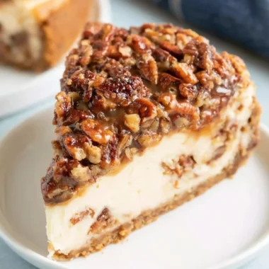 Delicious slice of pecan pie cheesecake topped with caramel and pecans